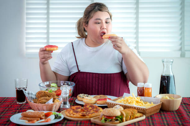 gadis gemuk asia lapar dan makan junk food di atas meja - junkfood potret stok, foto, & gambar bebas royalti