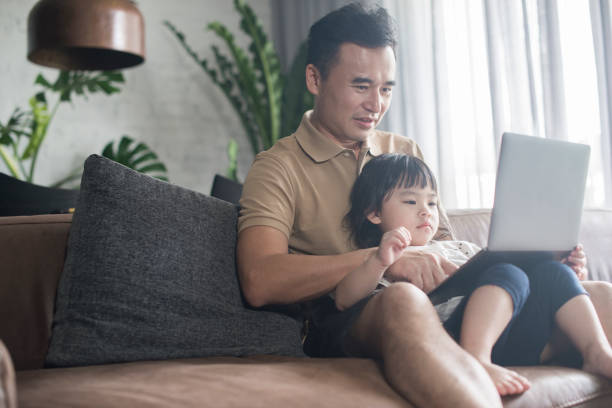 Asian Father and Daughter Looking At Laptop stock photo