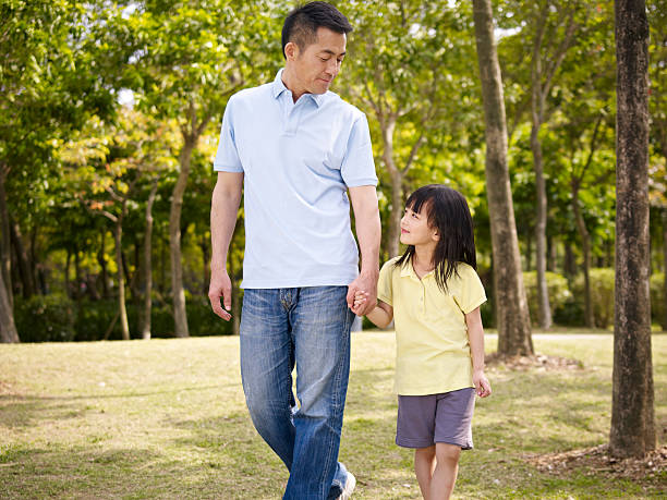 asian father and daughter takes a walk in park asian father and elementary-age daughter enjoying a walk in nature. child korea little girls korean ethnicity stock pictures, royalty-free photos & images