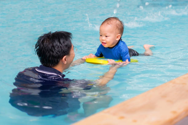 aziatische vader nemen schattige kleine aziatische 18 maanden/1 jaar oude peuter baby jongenskind zwemmen klasse - swimming baby stockfoto's en -beelden