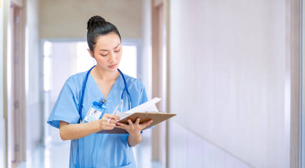 Asian female doctor is looking at the patient medical record after pay a ward visit for better healing examination and future nursing care plan treatment concept with copy space stock photo