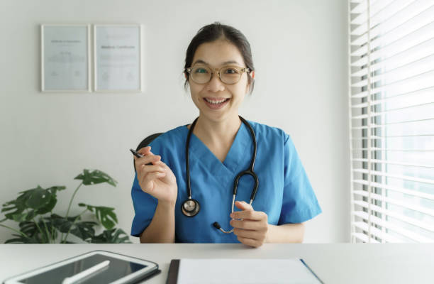 Asian Female Doctor making online video chat giving advice with her patient stock photo
