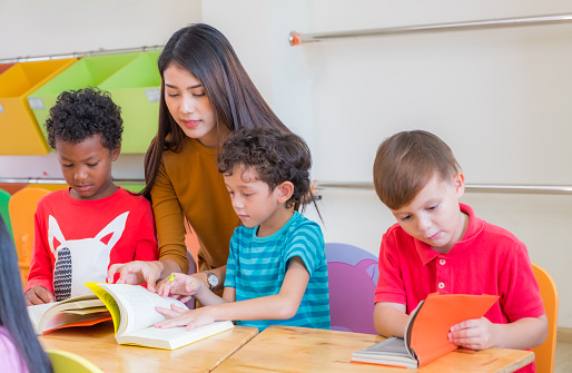 Asian Female Teacher Teaching Diversity Kids Reading Book