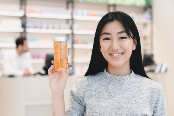 asian female young customer buyer client showing drug medicine jar, pills, painkillers, antibiotics at camera in pharmacy drugstore - två burkar piller bildbanksfoton och bilder