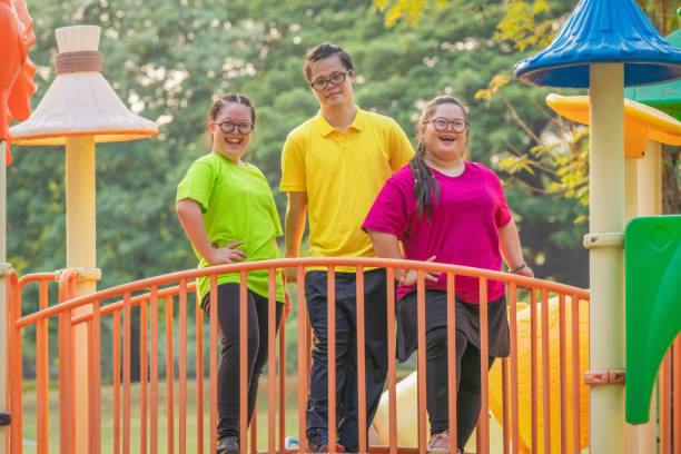 asian friends with autistic or down syndrome playing together at playground group of asian people friends with autistic or down syndrome having fun playing together at playground in park for recreation down syndrome stock pictures, royalty-free photos & images