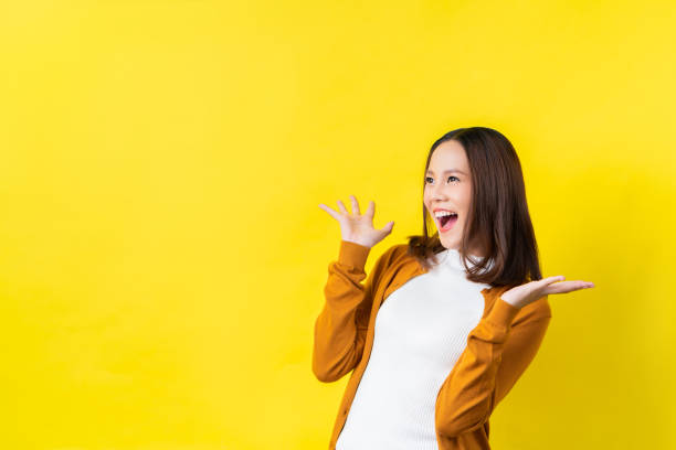 asiatisk tjej är förvånad hon är upphetsad. gul bakgrund studio - majestätisk bildbanksfoton och bilder