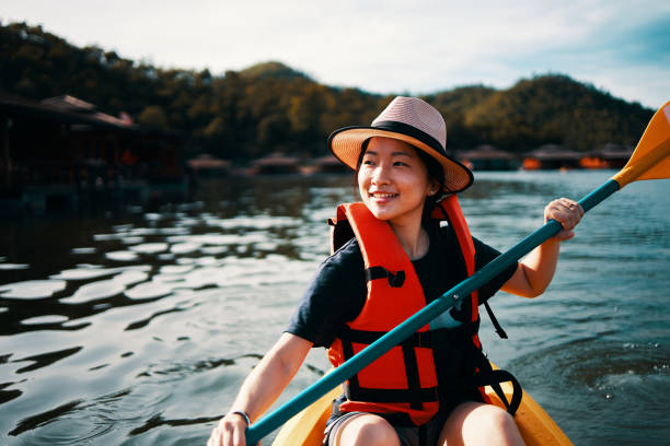 Asian girl is using action camera while kayaking at Kanchanaburi, Thailand. stock photo