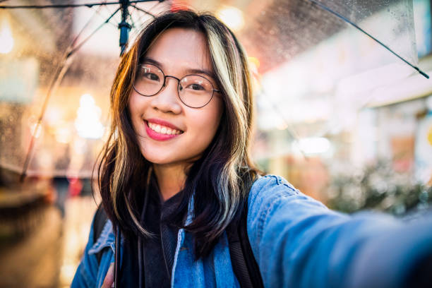 Asian girl taking a selfie in rain stock photo
