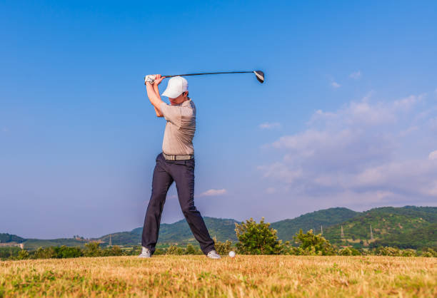 Asian golfer hitting golf ball on green fairway stock photo
