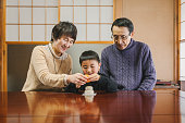 丸い餅にマンダリンオレンジを置くアジアの祖父母と孫