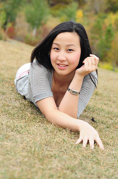 Asian lady laying down on grass stock photo