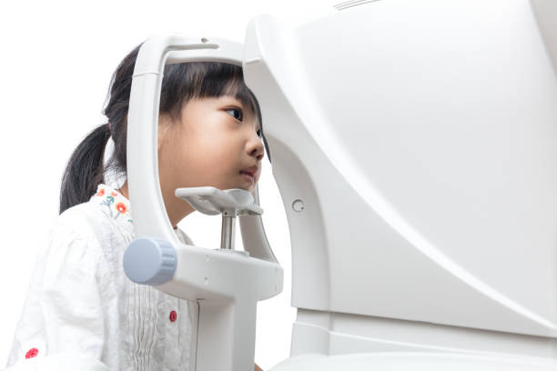 Asian Little Chinese Girl Doing Eyes Examination Through Auto refractometer stock photo