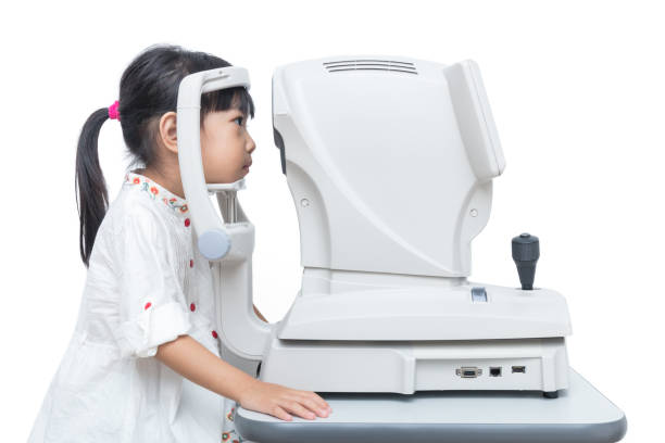 Asian Little Chinese Girl Doing Eyes Examination Through Auto refractometer stock photo