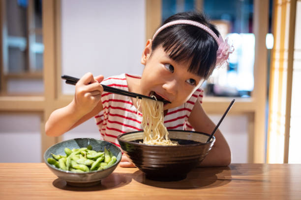 Asian little Chinese girl eating ramen noodles stock photo
