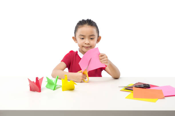 Asian little girl cutting a paper stock photo
