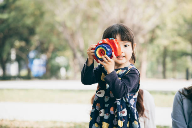 亞洲小女孩玩玩具相機在公園圖像檔