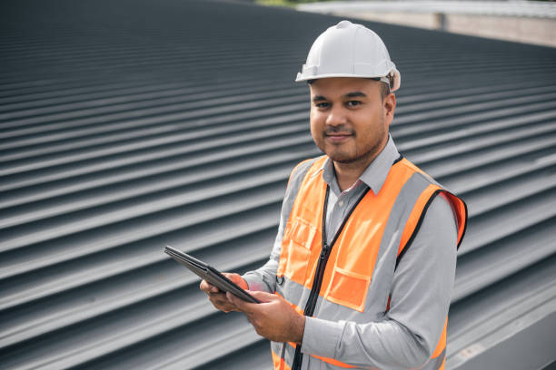 Asian male architect or engineer using tablet control planning construction building. Civil engineers work on the roof of a modern building. Standing on the top floor roof with the sunset stock photo