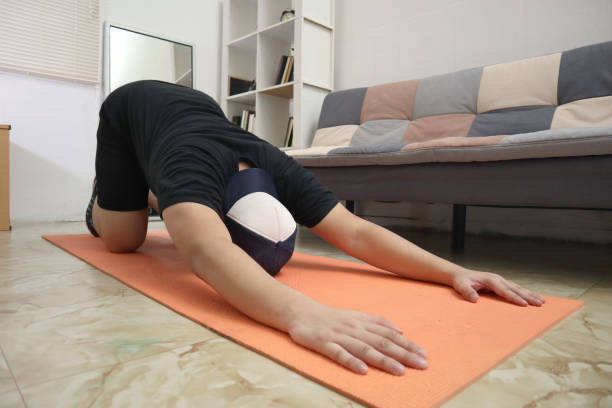 homens asiáticos fazendo exercícios em casa para se manterem saudáveis em um novo estilo de vida normal, treino caseiro interno, alongamento para flexibilidade - lombar - fotografias e filmes do acervo
