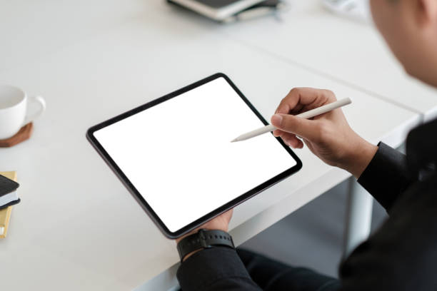 Asian male drawing on a white blank screen computer tablet with pen stylus stock photo