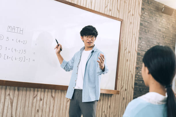 Asian male teacher teaching students at the classroom stock photo