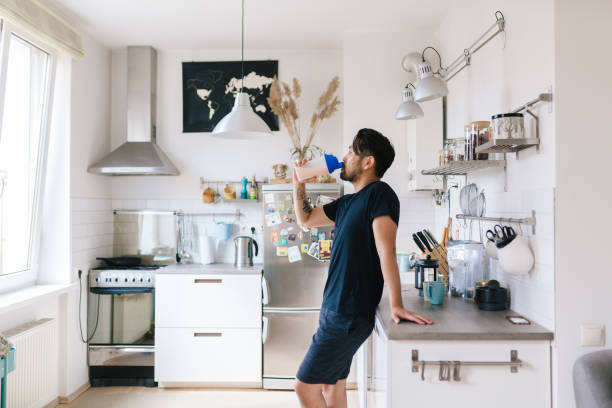 Asian man drinks protein shake after home workout Photo series of a japanese man working out at home, watching youtube videos and learning the exercises. protein stock pictures, royalty-free photos & images