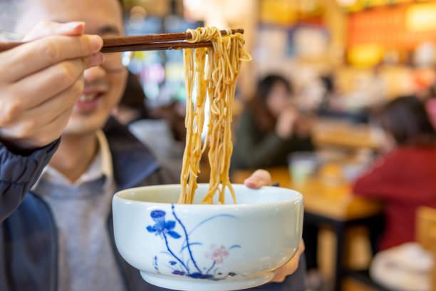 Asian man eating noodles with crab roe and shrimp stock photo