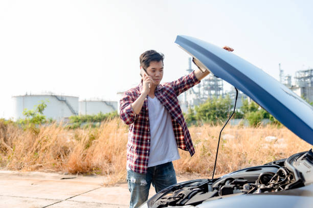 Asian man is talking on the phone for help due to a broken car during the trip. stock photo