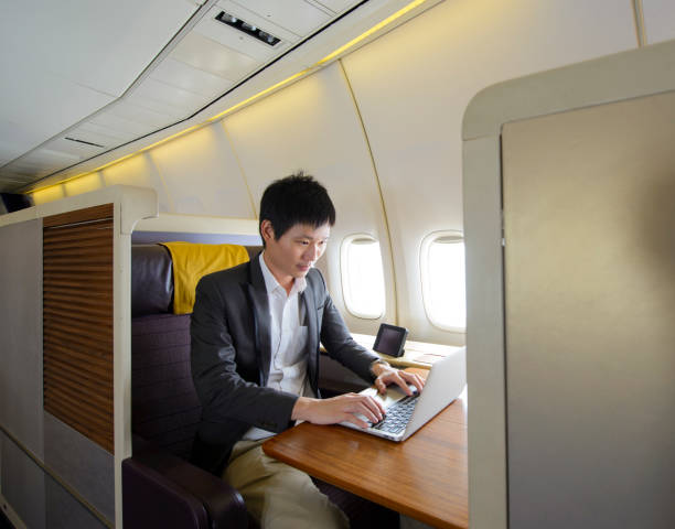 Asian man working with laptop on first class airplane stock photo