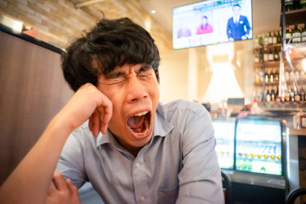 Asian man yawning in a restaurant. stock photo