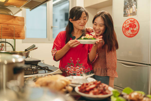 Asian mother and daughter bonding during food preparation for Chinese New Year's eve reunion dinner stock photo