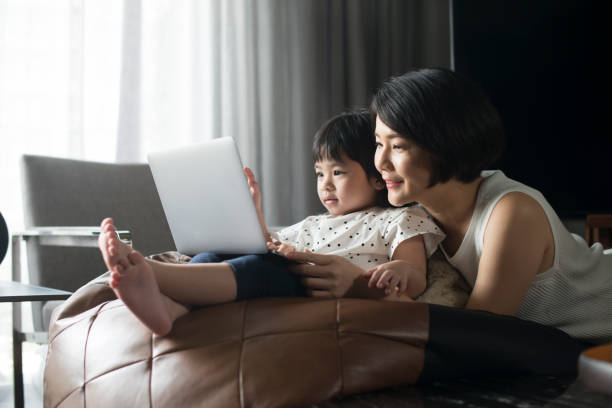 Asian Mother and Daughter Looking At Laptop stock photo