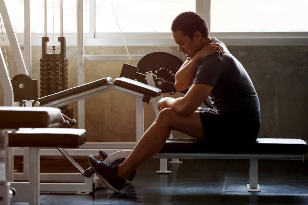 asiatiska muskulös man lider av axel skada medan du tränar på gymmet i morgon ljuset. träning, övningar, bodybuilder utbildning, sport kille gnugga hans rygg och nacke smärta.  ryggvärk - muskel bildbanksfoton och bilder