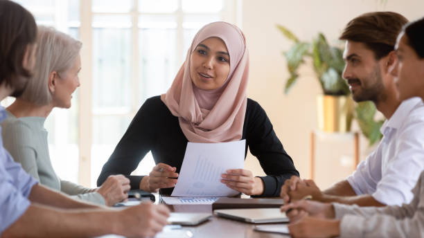 Asian muslim businesswoman executive wear hijab leading corporate briefing Young asian muslim businesswoman executive wear hijab discussing paperwork financial results consult clients employees group explain project plan at corporate briefing sit at company meeting table hijab stock pictures, royalty-free photos & images
