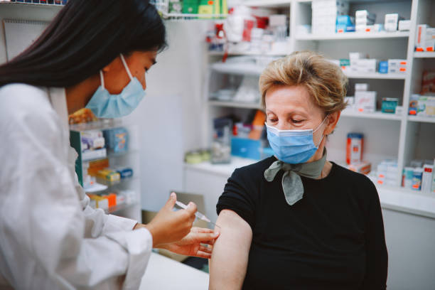 先輩患者にインフルエンザワクチンを与えるアジアの看護師 - ドラッグストア ストックフォトと画像