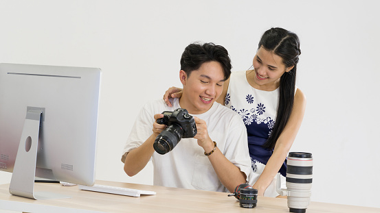 Asian photographers allow models to view pictures taken on the camera screen. The young model is very satisfied with her photo. The atmosphere in the photo studio.