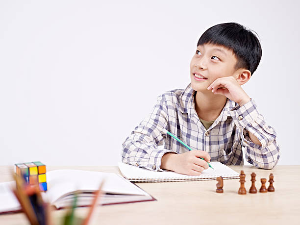 asian schoolboy studying 10 year-old asian elementary schoolboy looking away while studying. korean culture photos stock pictures, royalty-free photos & images