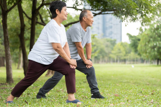 Asian Senior man and woman doing exercise at park outdoor in the morning. stock photo