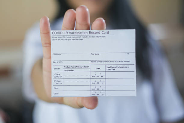 Asian Senior Woman Holding a COVID-19 Vaccination Record Card Close-up front view shot of unrecognizable Asian senior woman holding a COVID-19 vaccination record card. cdc vaccine card stock pictures, royalty-free photos & images