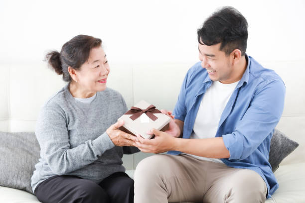 Asian Son give some present box to mother in living room smile and happy face in mother day stock photo