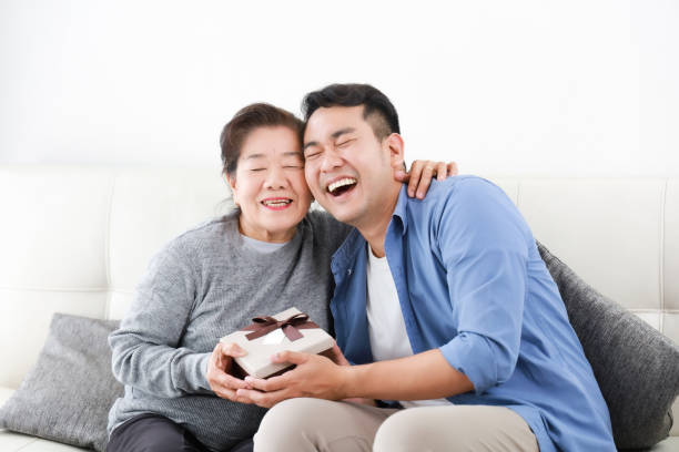 Asian Son give some present box to mother in living room smile and happy face in mother day stock photo