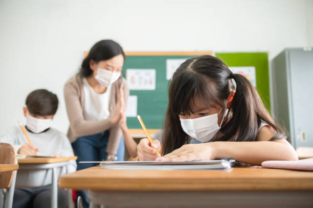 Asian student girl wearing protective face masks studying in classroom at the primary international school during COVID-19 pandemic stock photo
