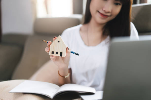 Asian student woman hand holding wooden house model. stock photo