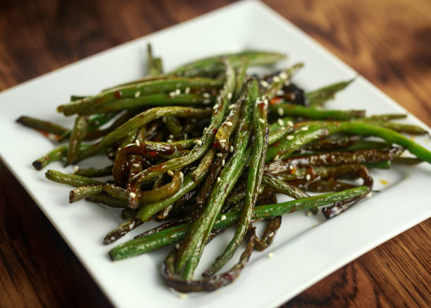 asian style Stir fried green beans with worcester sause and sesame seeds in white square plate asian style Stir fried green beans with worcester sause and sesame seeds in white square plate. green bean stock pictures, royalty-free photos & images