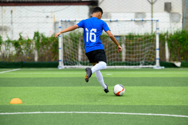 Asian teenager Football Players In Blue practicing football at the training ground stock photo