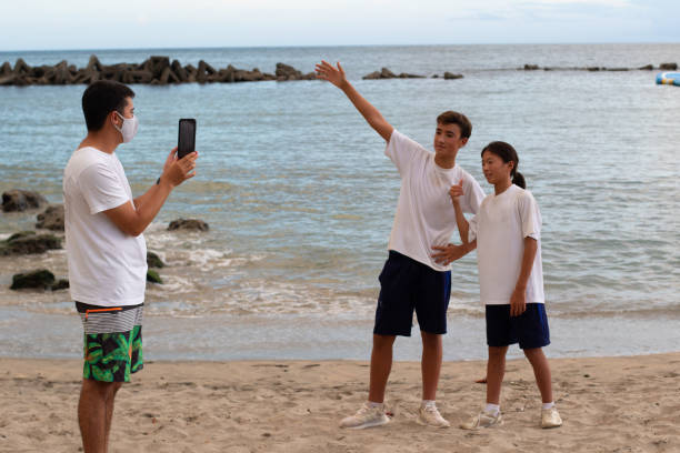 aziatische tieners met mobiel apparaat op het strand dat pret heeft die spelen spelletjes speelt - beach game group stockfoto's en -beelden