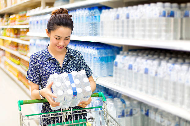 Asian woman buys in the supermarket bottle of water stock photo