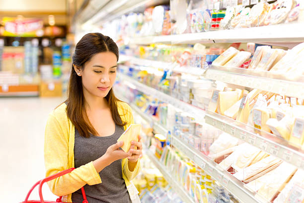 Asian woman buys in the supermarket cheese. stock photo