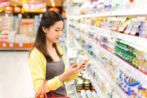 Asian woman buys in the supermarket yogurt stock photo