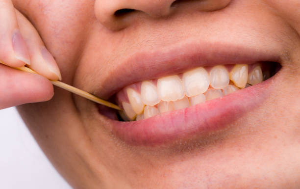 Asian woman clean her teeth from food stuck her teeth with bamboo wood toothpick after breakfast, lunch, dinner. Personal dental care with Asian style. Dental health and bad breath problem concept. stock photo