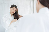 鏡の前で髪をとかすアジアの女性